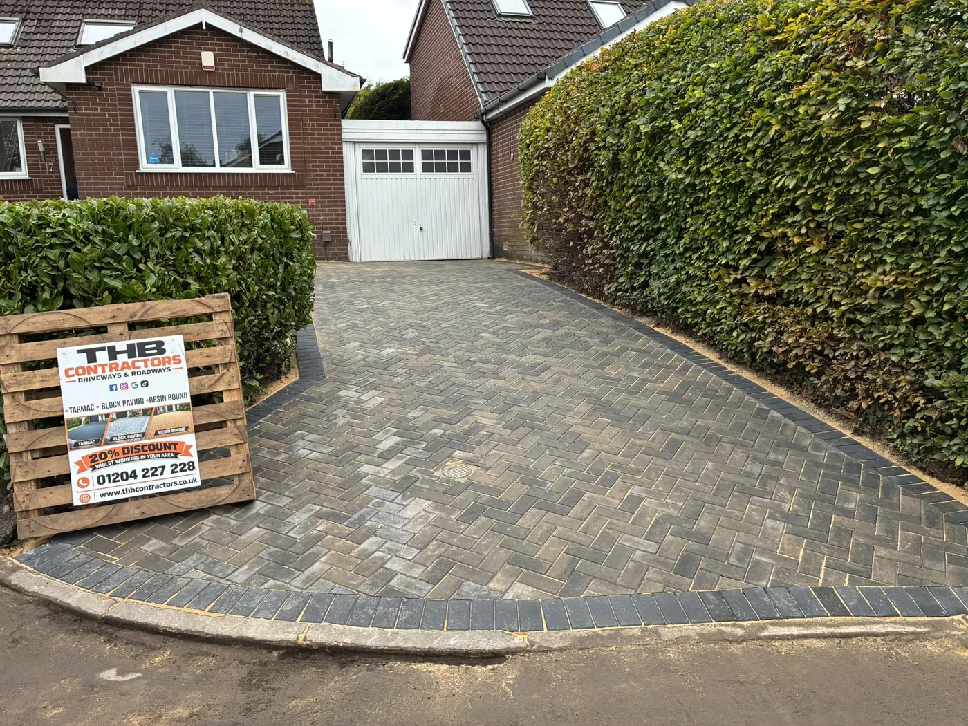 After: a worn concrete drive replaced with a herringbone block paved driveway and a charcoal border.
