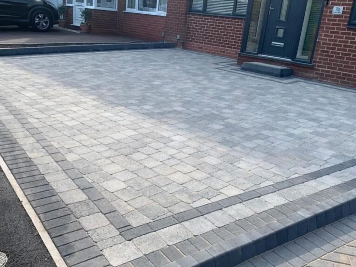 Grey block paved driveway with a charcoal border and a light edging course, laid up to the front door